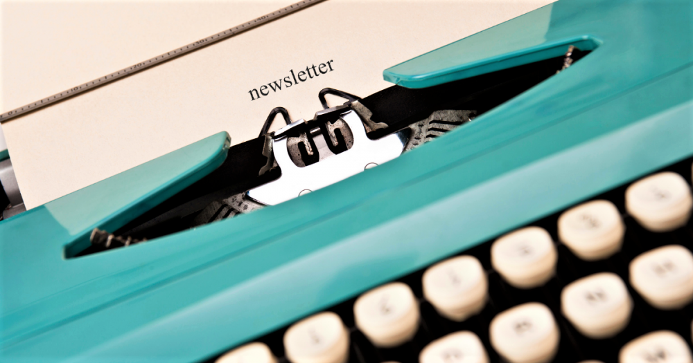 teal vintage typewriter with paper inserted containing word newsletter