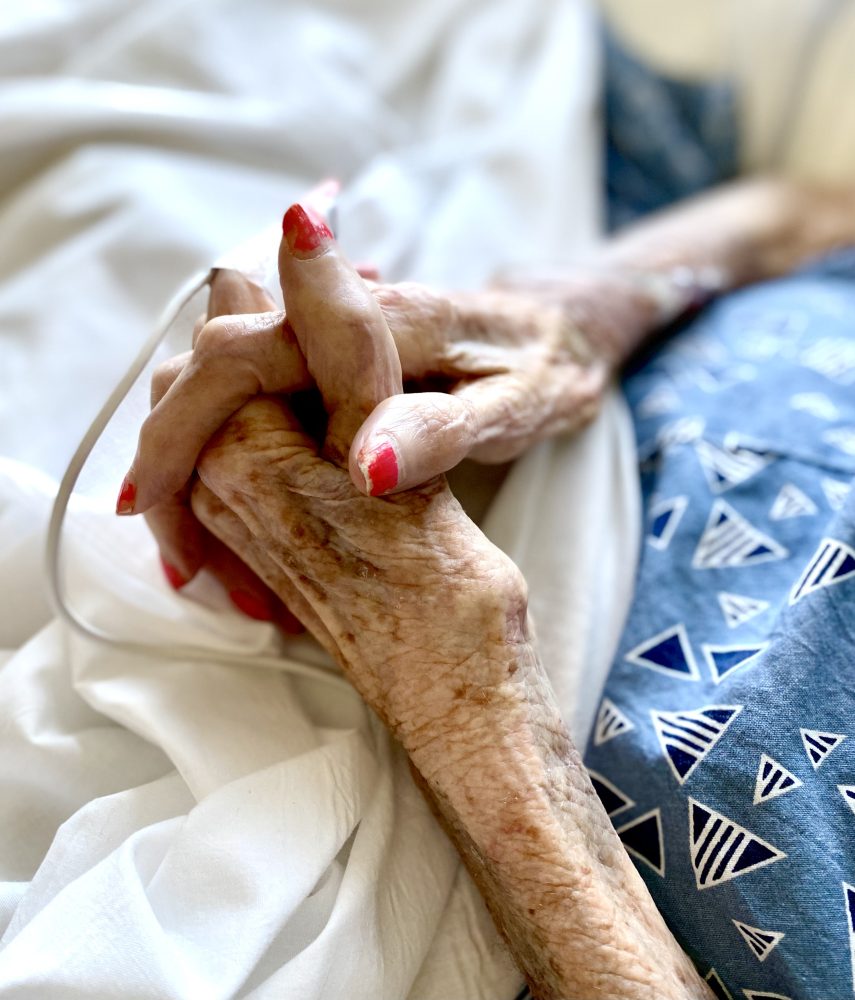 an old woman's hands clasped as she lay in her hospital bed