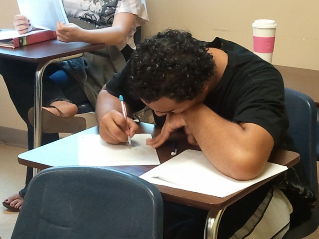 High school student writing at his desk after he is reminded to just write