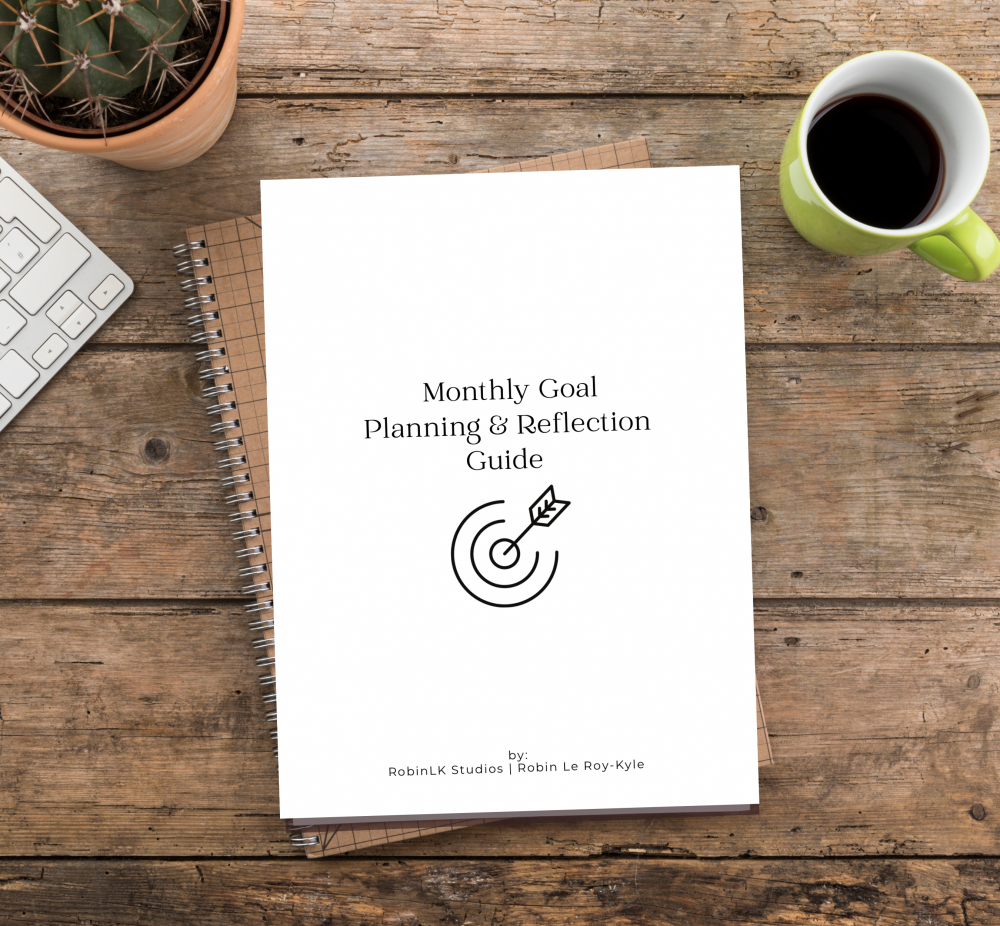 cover of a free resource titled Monthly Goal Planning and Reflection Guide - sitting on a wood table with a cup of coffee and keyboard